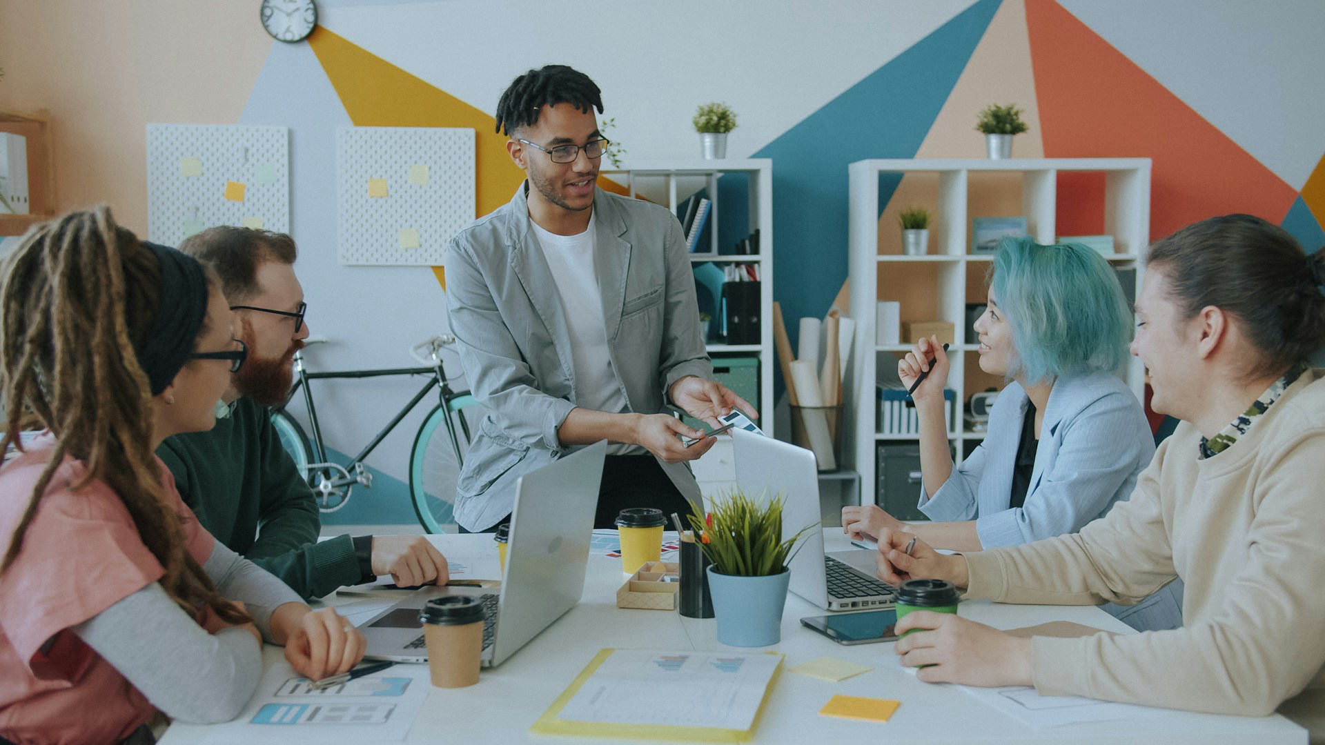 A team around a table with laptops, one colleague presenting a chart